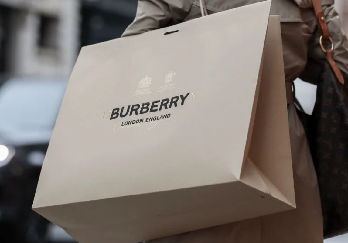 Femeie in trenci care tine o punga Burberry pe umar