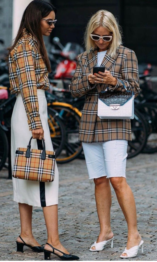 Doua tinere uitandu-se la un telefon, pe strada
