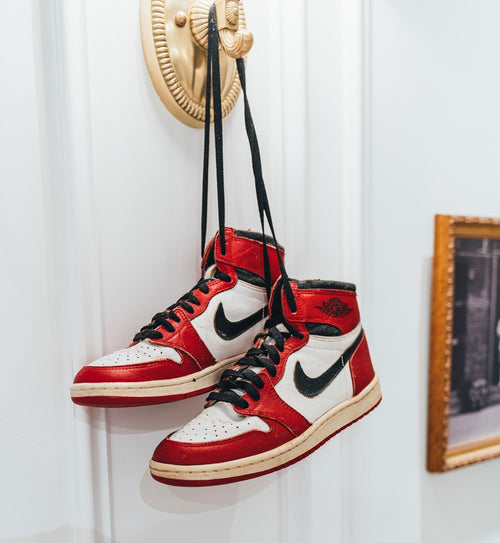 Adidasi Nike Air Jordan agatati in cuier pe usa, langa un tablou